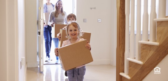 a family carrying boxes in their new home
